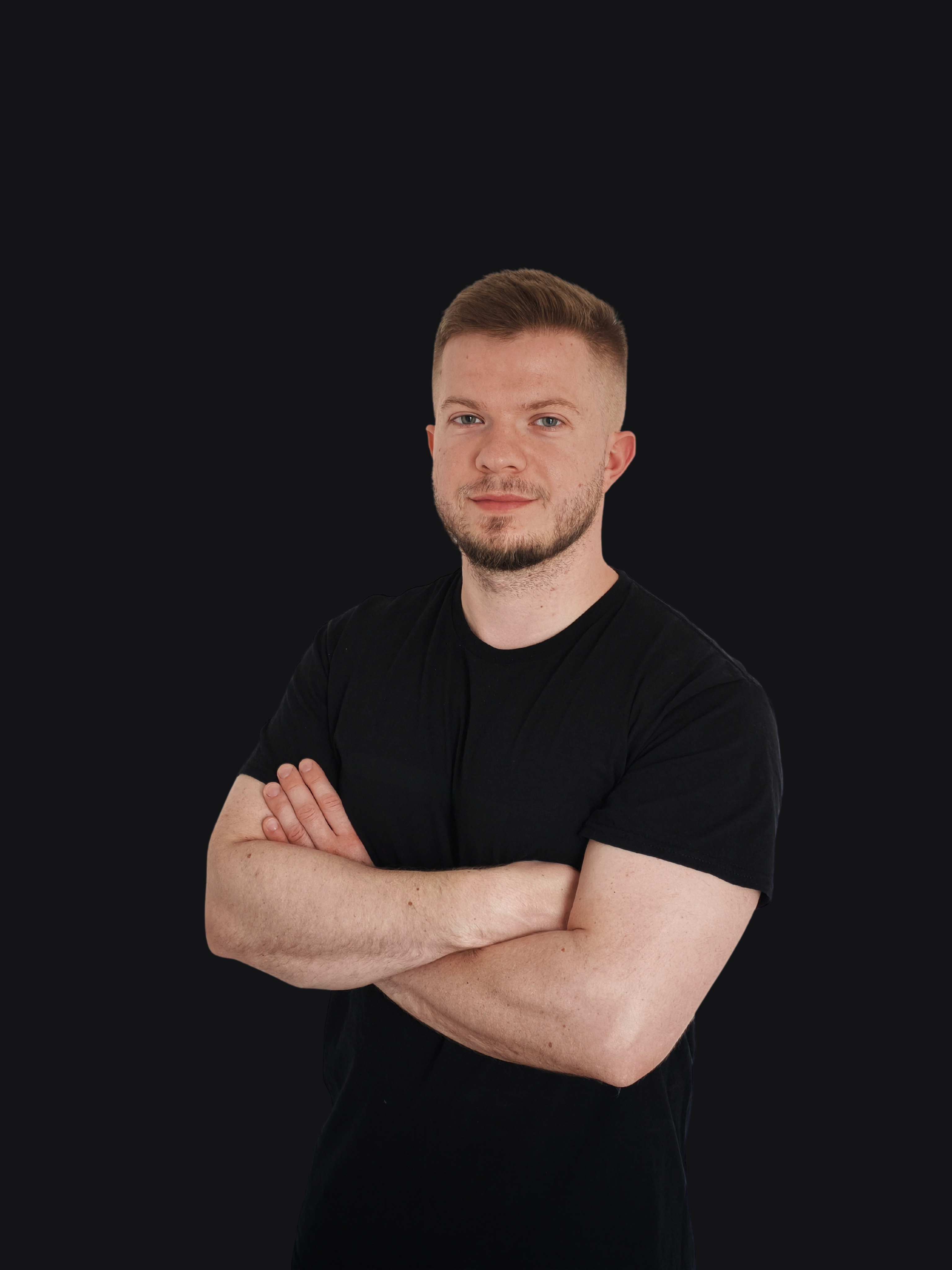 Uśmiechnięty trener personalny z tłem, które płynnie i bezramkowo przechodzi w ciemne tło strony o kolorze głębokiej czerni i grafitu.